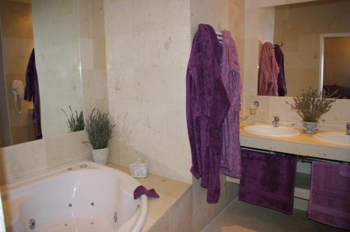 a bathroom with a tub and two sinks and purple towels at Château de Pommeuse in Pommeuse