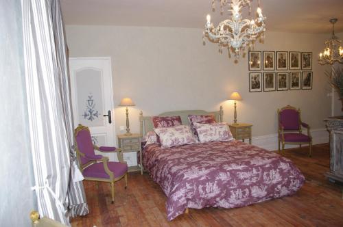 a bedroom with a bed and two chairs and a chandelier at Château de Pommeuse in Pommeuse
