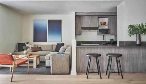 a living room and kitchen with a couch and stool at Pendry Park City in Park City