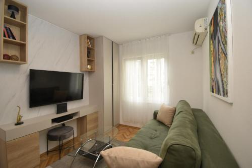 a living room with a green couch and a television at Studio apartment Art Zone in Podgorica