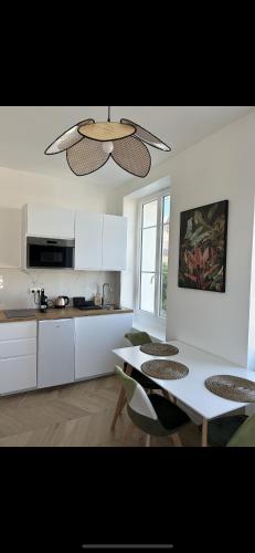 une cuisine avec des armoires blanches et une table et des chaises dans l'établissement La marine, à Deauville