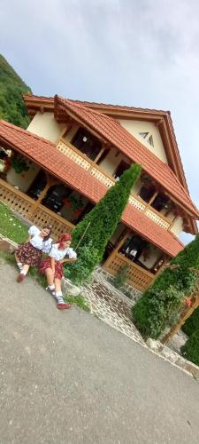 two people standing in front of a building at Pensiunea Valea Branzei in Năneşti