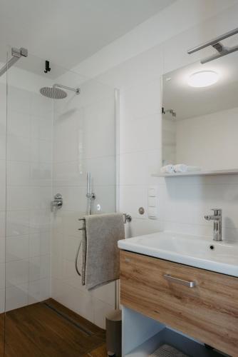 a white bathroom with a sink and a shower at Wein Cottage Kellerstöckl in Eisenberg an der Pinka