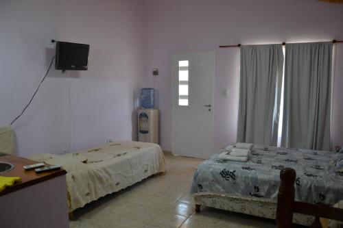 a room with two beds and a desk and a television at Cabañas Comarca del Colorado in Río Colorado