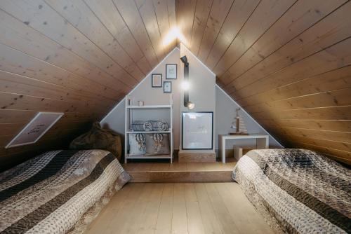 two beds in a attic bedroom with wooden ceilings at Wein Cottage Kellerstöckl in Eisenberg an der Pinka