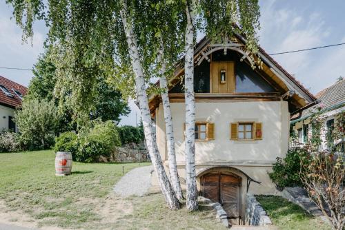 ein Haus mit einem Baum davor in der Unterkunft Wein Cottage Kellerstöckl in Eisenberg an der Pinka