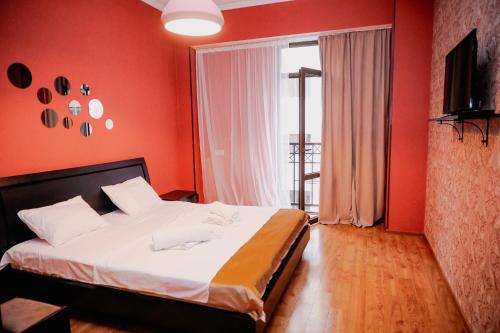 Un dormitorio con una cama con paredes rojas y una ventana. en Avlabari Apartment - NEW ONE, en Tiflis