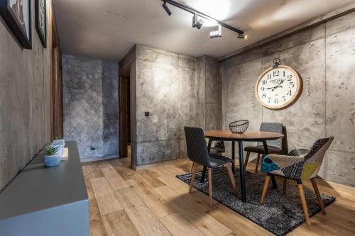 a dining room with a table and chairs and a clock at Bella Roe Premium Apartments in Belgrade