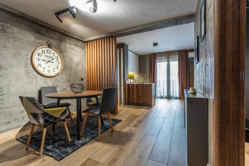 a dining room with a table and chairs and a clock at Bella Roe Premium Apartments in Belgrade