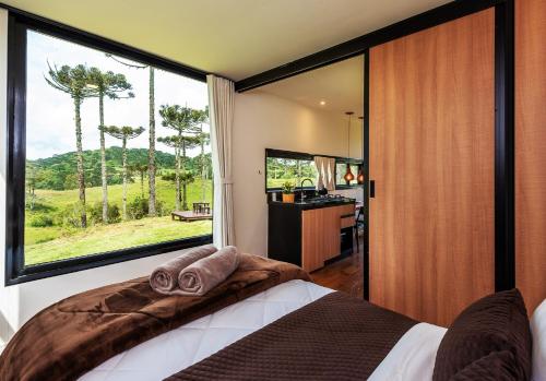 um quarto com uma cama e uma grande janela em Brumas Casa de Campo - Cambará do Sul em Cambará