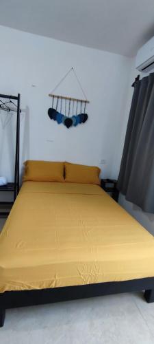 a bed in a room with a yellow bedspread at Casa en Mahahual cerca de la playa D3 in Mahahual