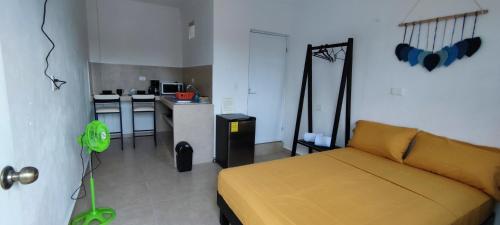 a bedroom with a yellow bed and a kitchen at Casa en Mahahual cerca de la playa D3 in Mahahual