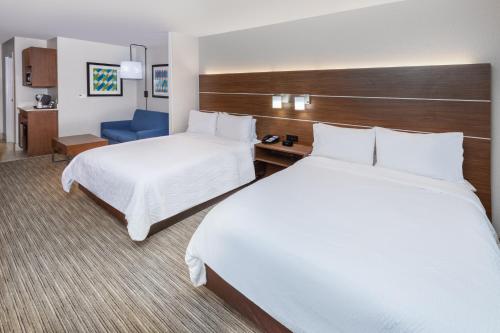 a hotel room with two beds and a blue chair at Holiday Inn Express & Suites Lafayette South by IHG in Lafayette