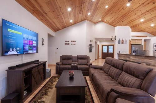 a living room with a couch and a big screen tv at Hillside Hideaway - game rm - master spa - Luxury in Lake Arrowhead