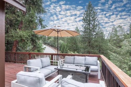 a deck with a table and chairs and an umbrella at Hillside Hideaway - game rm - master spa - Luxury in Lake Arrowhead