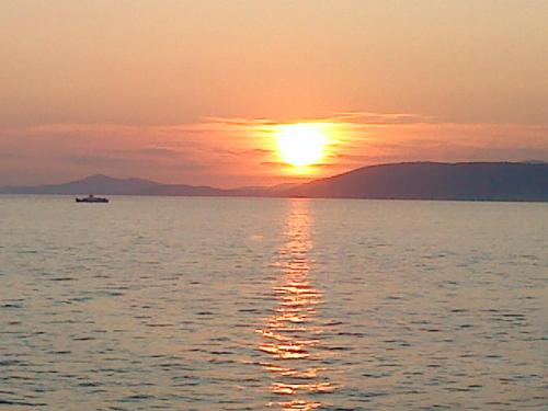 a sunset over a large body of water with a boat at Luxury Villa Sun Stone heated pool & whirlpool in Trogir