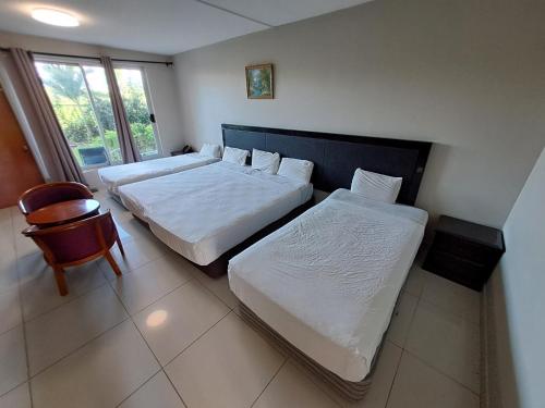 a bedroom with two beds and a chair and a window at Trans International Hotel in Nadi