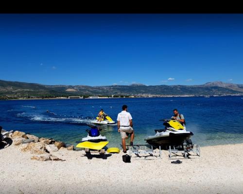 a group of people on a beach with boats in the water at Luxury Villa Sun Stone heated pool & whirlpool in Trogir