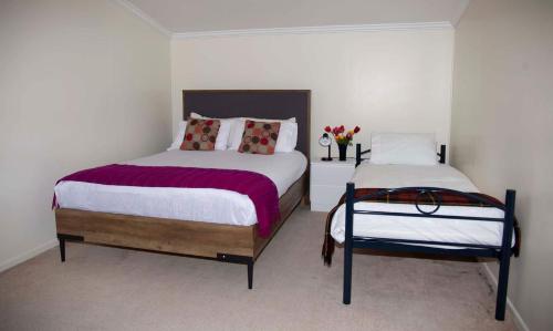 a bedroom with two beds and a vase of flowers at Surat Bay Lodge by the Sea/Backpackers Hostel in Owaka