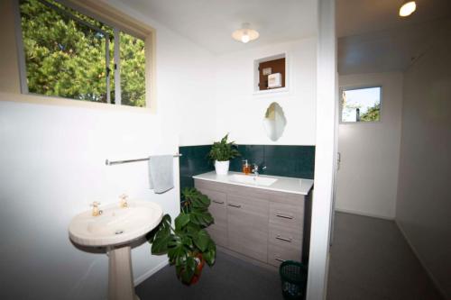 Baño blanco con lavabo y espejo en Surat Bay Lodge by the Sea/Backpackers Hostel en Owaka