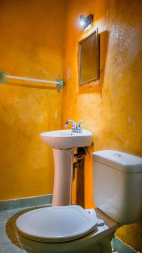a bathroom with a white toilet and a sink at Hotel Mucuy in Mérida