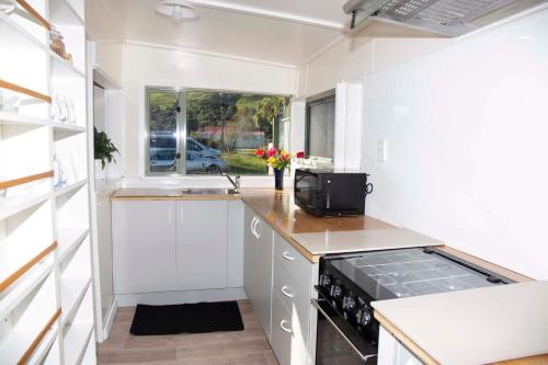 a small kitchen with white cabinets and a stove at Surat Bay Lodge by the Sea/Backpackers Hostel in Owaka
