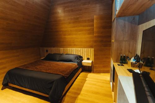 a bedroom with a bed in a room with wooden walls at Oculto refugio de bosque in Envigado