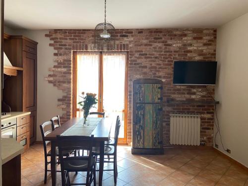 a kitchen with a dining room table and a brick wall at Casa Luisini in Mondovì