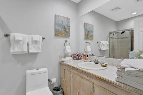 een witte badkamer met een wastafel en een spiegel bij 4636 Whimbrel Lane in Fernandina Beach