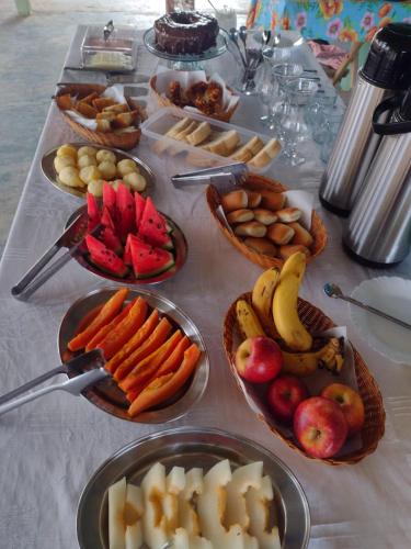 a table with many plates of fruit and vegetables on it at Pousada o Canto da Seriema in Nobres