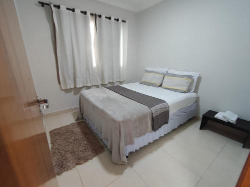 um pequeno quarto com uma cama e uma janela em Residencia Cidade Verde 14 em Maringá