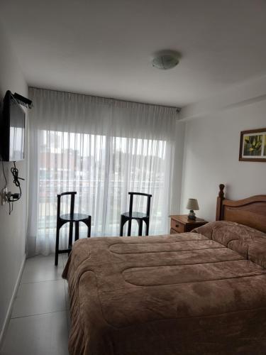 1 dormitorio con 1 cama, 2 sillas y ventana en Bellagio Tower, en Punta del Este