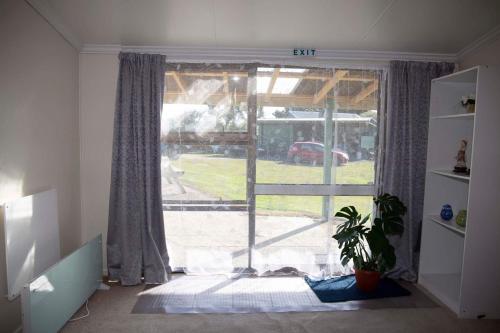 a living room with a large window and a plant at Surat Bay Lodge by the Sea/Backpackers Hostel in Owaka