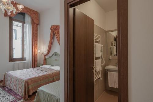 a bedroom with a bed and a sink and a mirror at Hotel al Sotoportego in Venice