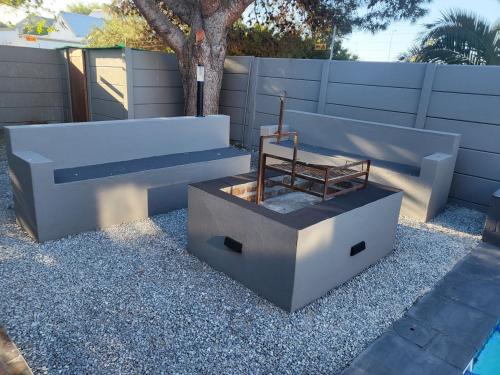 two benches sitting on gravel next to a fence at Willow Retreat Blouberg in Cape Town