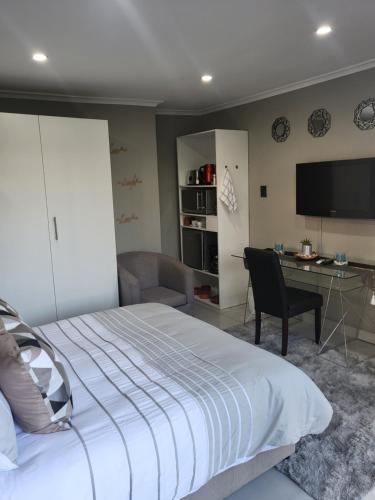 a bedroom with a bed and a desk and a television at Willow Retreat Blouberg in Cape Town
