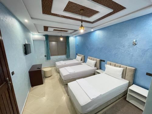 Cette chambre comprend 3 lits et un mur bleu. dans l'établissement IGHIZ INN resort, à Errachidia