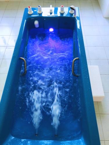 a jacuzzi tub with blue water in a bathroom at Vanadzor Armenia Health Resort & Hotel in Vanadzor