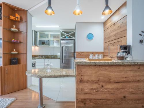 a kitchen with a counter and a refrigerator at Fascino 302 - Apartamento 600 metros Rua Coberta de Gramado in Gramado