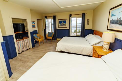 a hotel room with two beds and a tv at Auberge La Marmite in La Malbaie