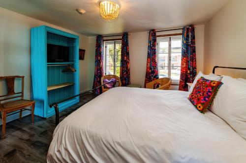 a bedroom with a bed and a blue cabinet and windows at Auberge La Marmite in La Malbaie