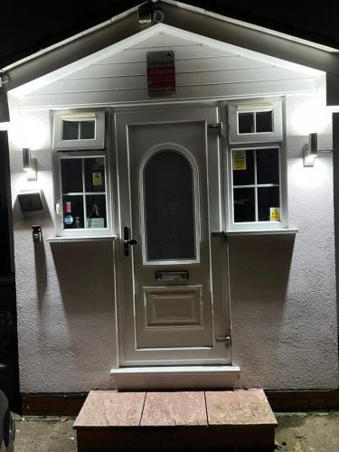 a white building with a door and two windows at Large Double Bedroom with free on site parking in Kingston upon Thames