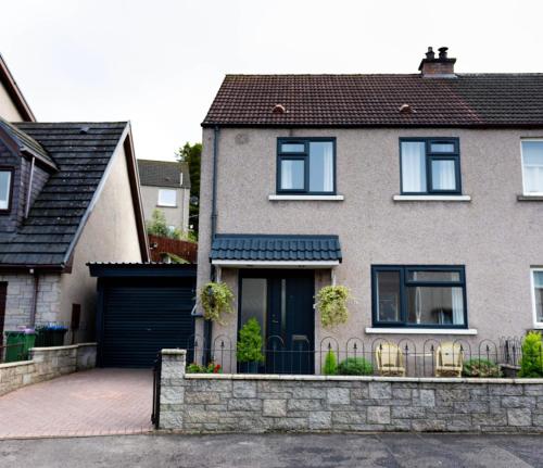 a brick house with a black garage at Lovely 2 bed house in Pitlochry in Pitlochry