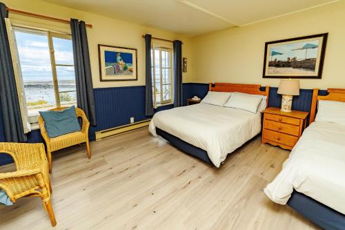 a bedroom with two beds and a table and a chair at Auberge La Marmite in La Malbaie