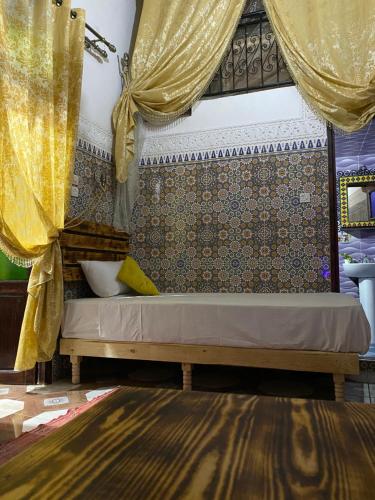 1 dormitorio con 1 cama con cortinas amarillas y alfombra en Riad Abqari Youssefi en Fez