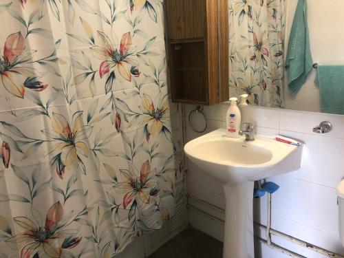 a bathroom with a sink and a flower shower curtain at Playa y Sol in Viña del Mar