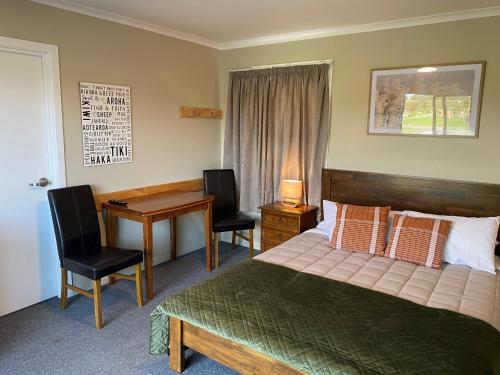 a bedroom with a bed and a desk with chairs at Hokitika Holiday Park in Hokitika