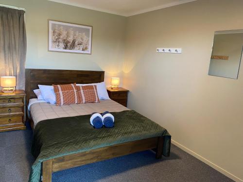 a bedroom with a bed with two blue shoes on it at Hokitika Holiday Park in Hokitika