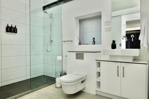 a white bathroom with a toilet and a shower at Eaglehawk Pavilions in Eaglehawk Neck