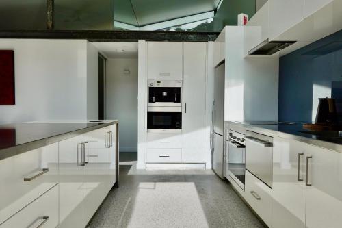 a white kitchen with white cabinets and appliances at Eaglehawk Pavilions in Eaglehawk Neck